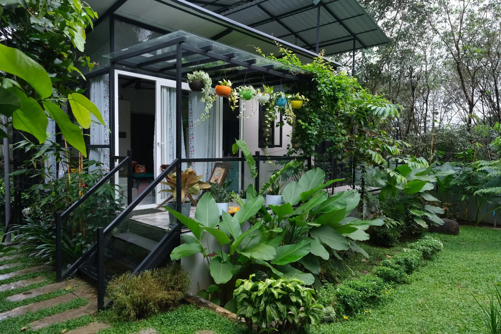 Front view of our small container home surrounded by a lush garden in Kerala
